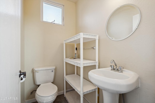 bathroom with toilet, baseboards, and a sink