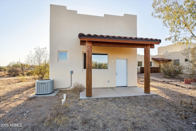 back of house featuring a patio, central AC unit, a tile roof, and stucco siding