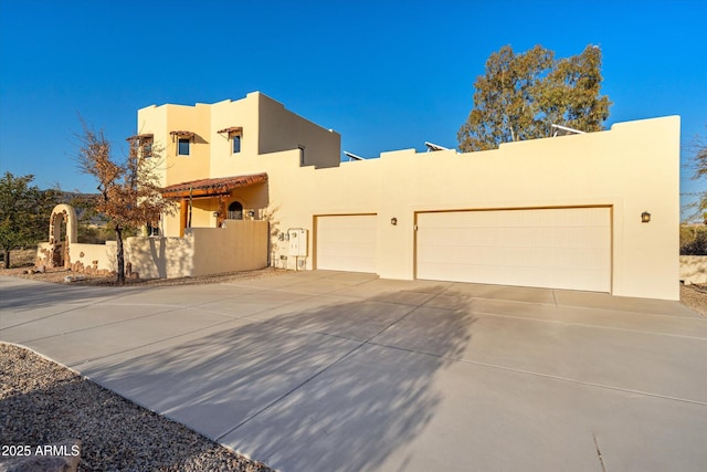 view of front of property featuring stucco siding, a garage, concrete driveway, and fence