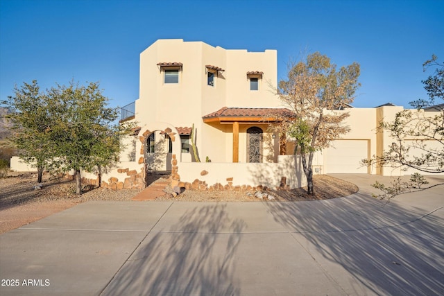 adobe home with a balcony, driveway, an attached garage, stucco siding, and a tile roof