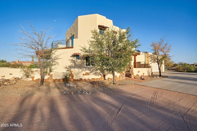 view of home's exterior featuring stucco siding, a balcony, and concrete driveway