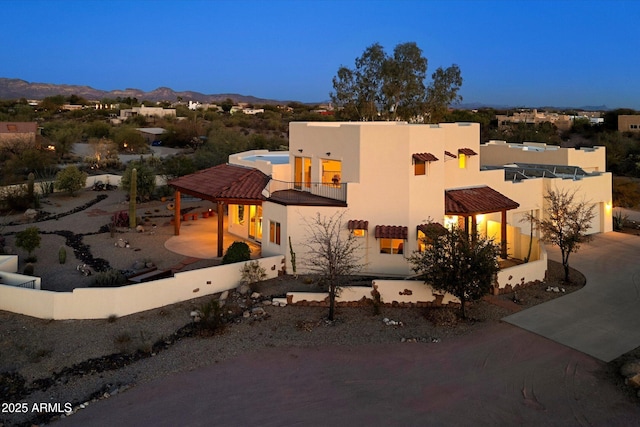 view of front facade featuring stucco siding, a mountain view, and a balcony