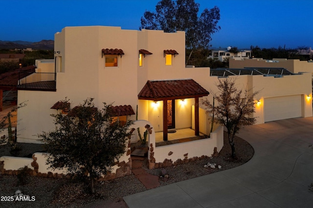 pueblo-style house featuring a garage, driveway, and stucco siding