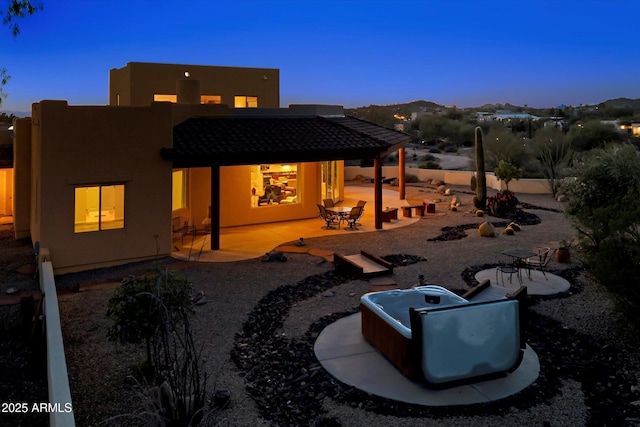 rear view of house with stucco siding, a patio, and a tile roof