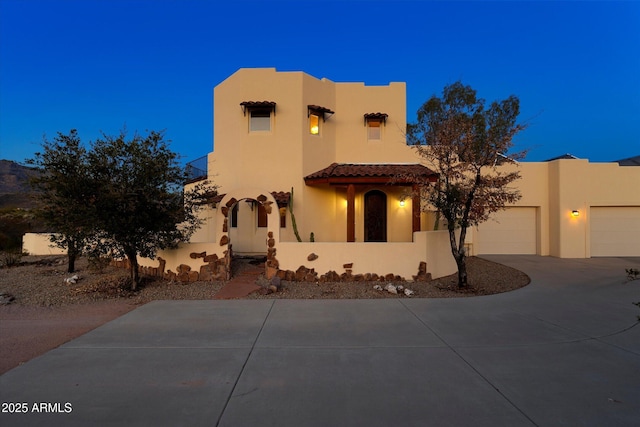 pueblo-style house with stucco siding and concrete driveway