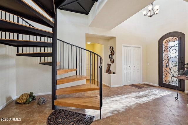 entryway with a notable chandelier, stairway, arched walkways, baseboards, and a towering ceiling