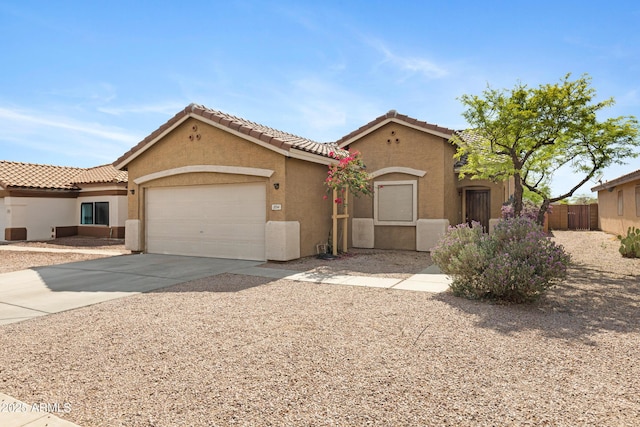 mediterranean / spanish home featuring an attached garage, stucco siding, driveway, and fence