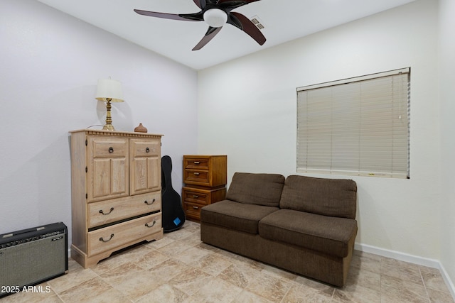 living area featuring a ceiling fan and baseboards