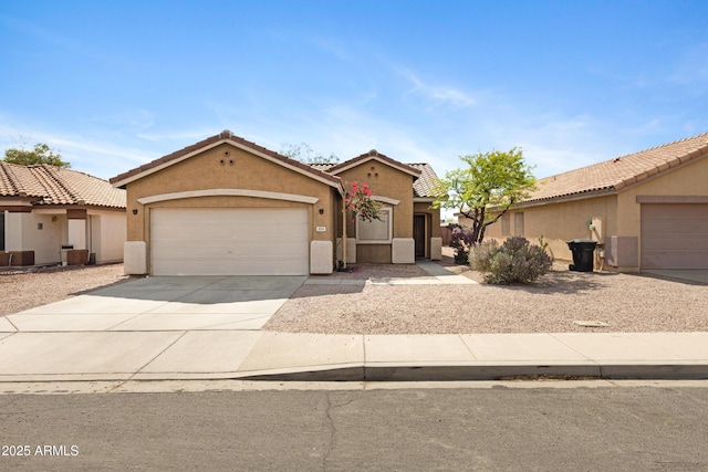 mediterranean / spanish-style house with stucco siding, an attached garage, a tiled roof, and driveway