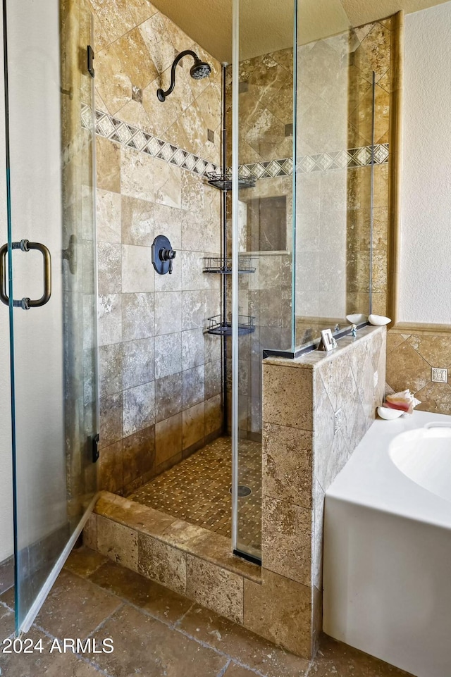 bathroom with tile walls, a textured ceiling, and separate shower and tub