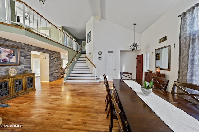 dining space featuring high vaulted ceiling, light wood-type flooring, and beam ceiling