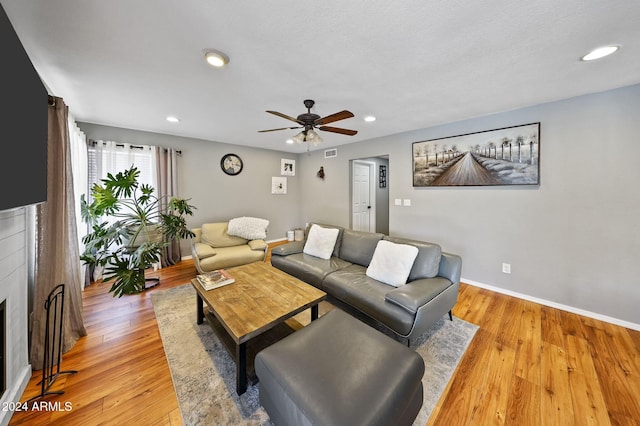 living room featuring light wood-type flooring, a textured ceiling, and ceiling fan