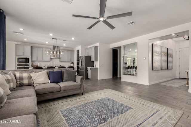 living room with ceiling fan with notable chandelier and light hardwood / wood-style flooring