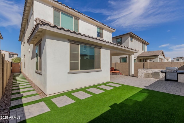 rear view of house with area for grilling, a yard, and a patio area