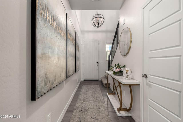 hallway featuring dark hardwood / wood-style flooring and an inviting chandelier