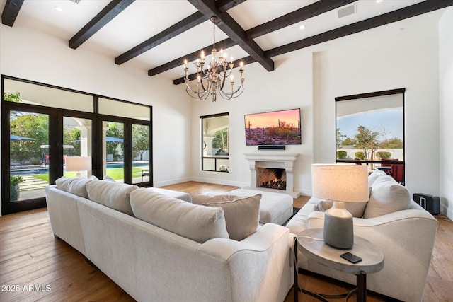 living area with a warm lit fireplace, visible vents, baseboards, and wood finished floors