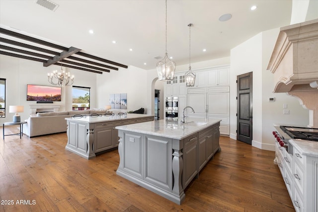 kitchen featuring a spacious island, visible vents, gray cabinets, and a sink