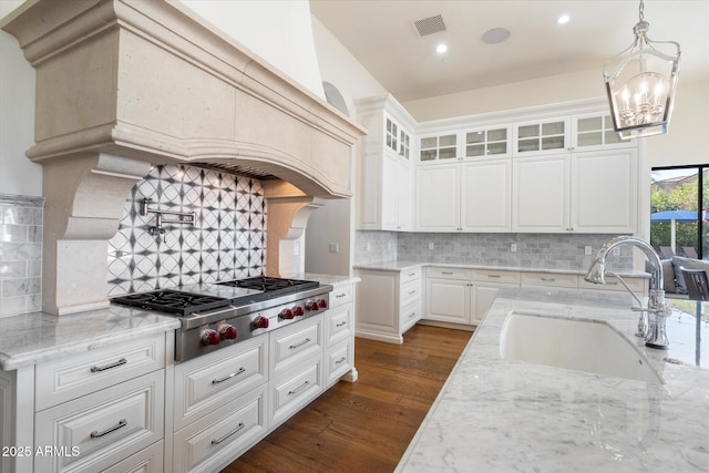 kitchen with stainless steel gas cooktop, light stone counters, a sink, and dark wood finished floors