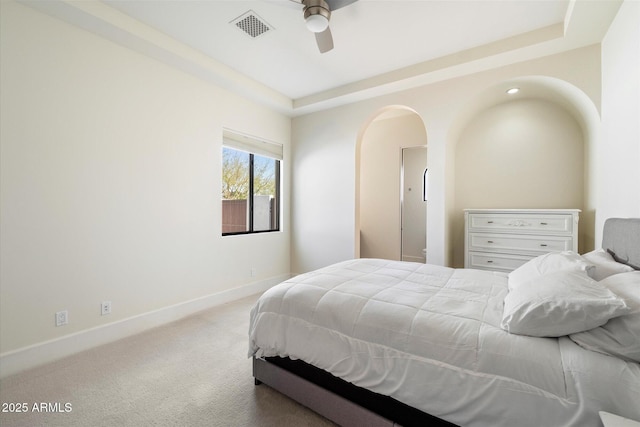 carpeted bedroom with visible vents, baseboards, a raised ceiling, and a ceiling fan