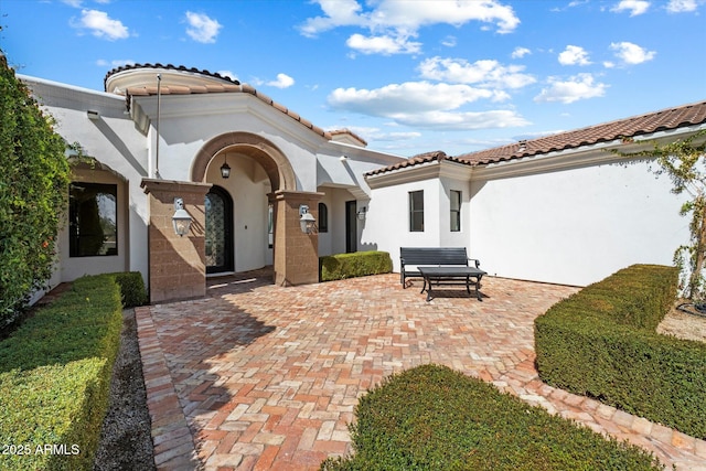 exterior space with a tiled roof, a patio area, and stucco siding