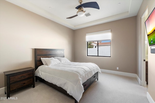 bedroom featuring baseboards, visible vents, a tray ceiling, and light colored carpet