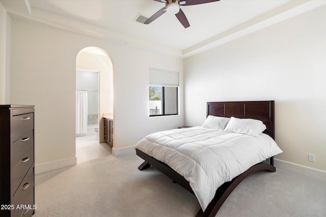 bedroom featuring arched walkways, a raised ceiling, visible vents, light carpet, and baseboards