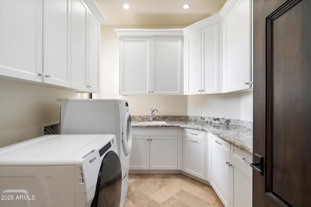 washroom featuring recessed lighting, a sink, cabinet space, stone finish flooring, and washing machine and clothes dryer