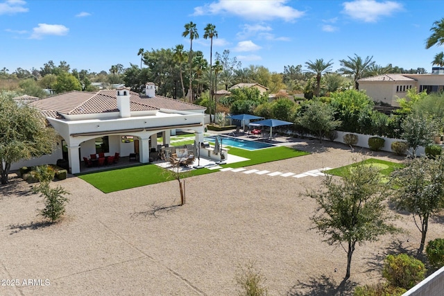 rear view of property with a tiled roof, a chimney, a patio area, and a fenced backyard