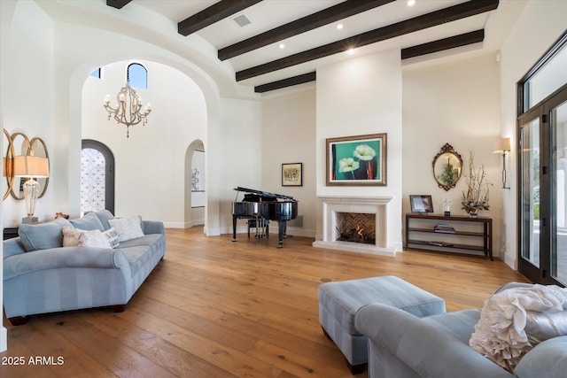 living room featuring a chandelier, light wood-type flooring, a warm lit fireplace, and baseboards