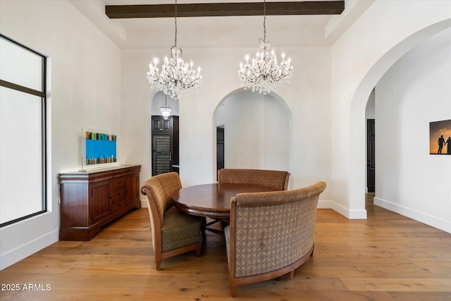 dining space with a high ceiling, beamed ceiling, light wood-style flooring, and baseboards