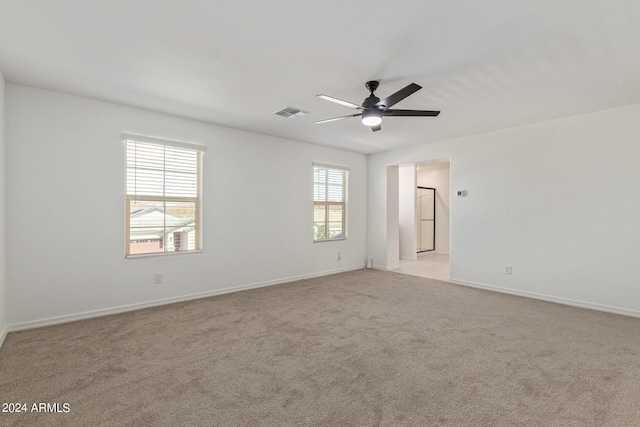 unfurnished room featuring ceiling fan, a wealth of natural light, and light colored carpet