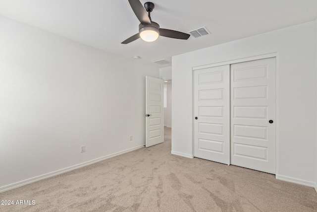 unfurnished bedroom with light colored carpet, a closet, and ceiling fan