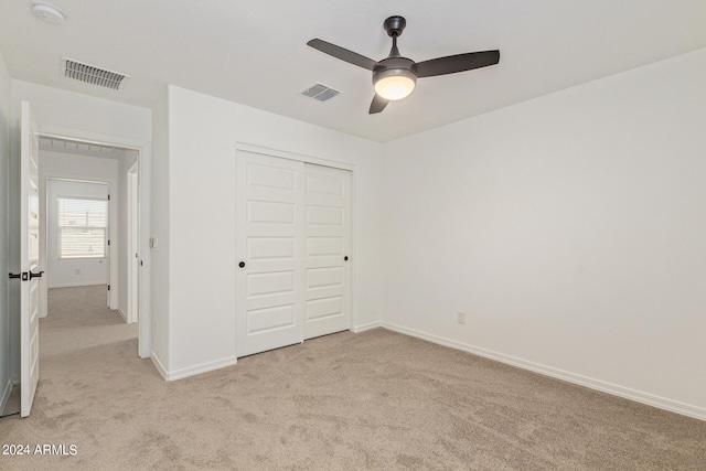 unfurnished bedroom featuring a closet, light colored carpet, and ceiling fan