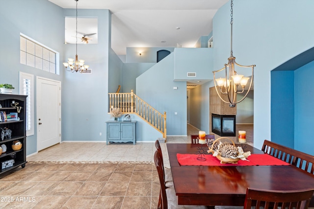 dining room featuring an inviting chandelier, stairway, visible vents, and a high ceiling