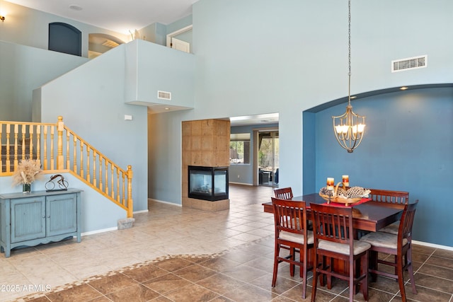 dining area with visible vents, a tile fireplace, stairs, and baseboards