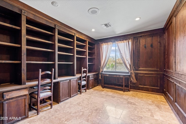 home office featuring visible vents, a textured ceiling, built in desk, recessed lighting, and wood walls