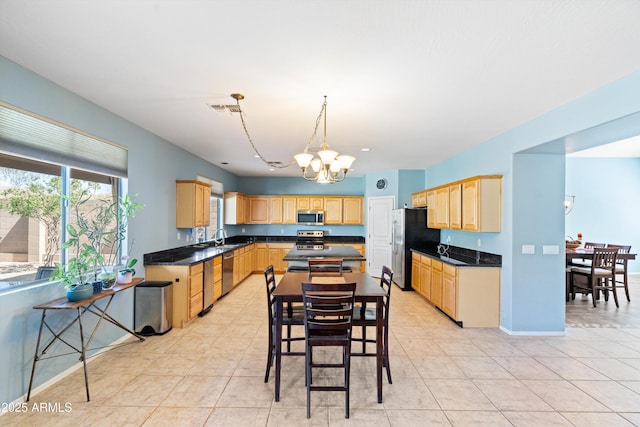 kitchen featuring dark countertops, visible vents, light brown cabinetry, appliances with stainless steel finishes, and a sink