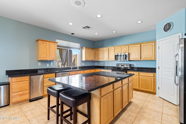 kitchen with a kitchen island, visible vents, light brown cabinets, and stainless steel appliances