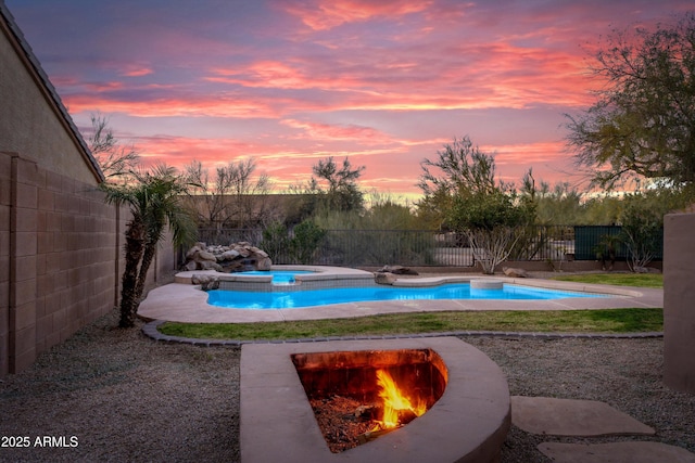 pool at dusk with a fenced in pool, an in ground hot tub, and a fenced backyard