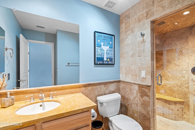 bathroom featuring visible vents, toilet, tile walls, and a stall shower