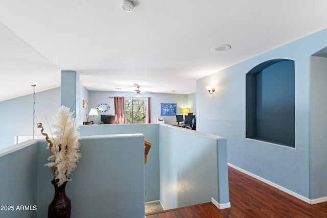 corridor featuring an upstairs landing, baseboards, and wood finished floors