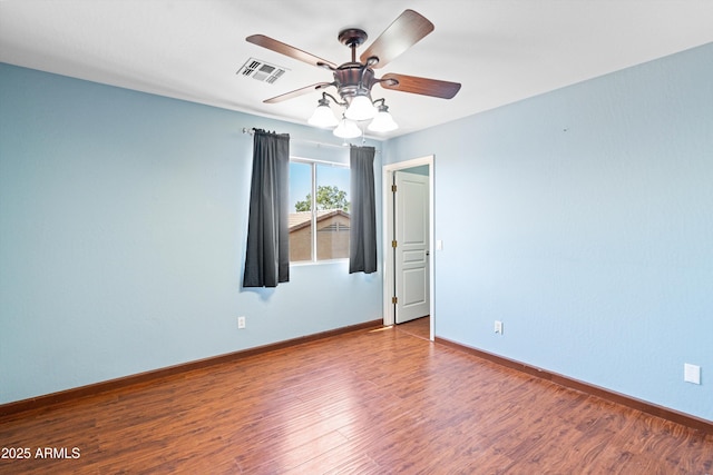 spare room featuring visible vents, baseboards, wood finished floors, and a ceiling fan