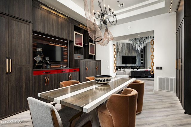 kitchen with light wood-style flooring, dark brown cabinetry, visible vents, and an inviting chandelier