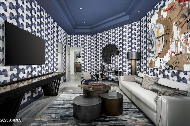 living room with wallpapered walls, a tray ceiling, wood finished floors, and recessed lighting