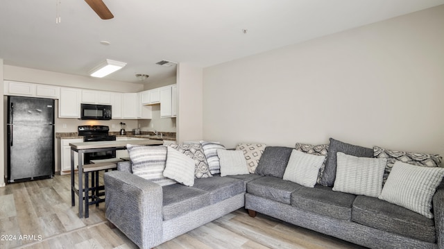 living room with light wood-type flooring and ceiling fan