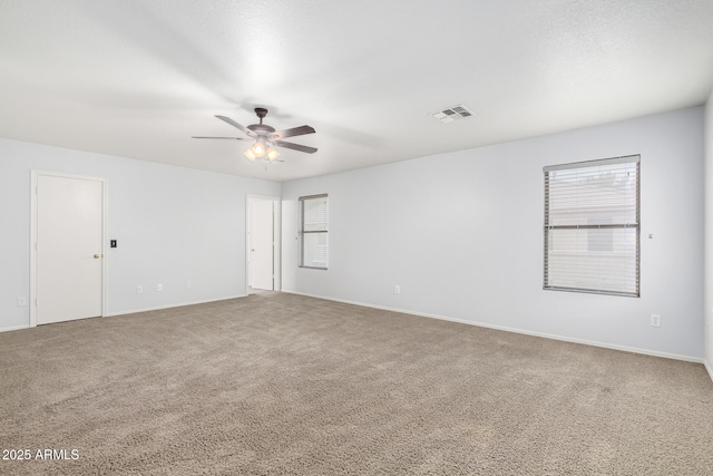 carpeted empty room with visible vents, ceiling fan, and baseboards