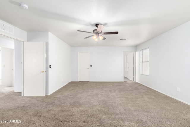 empty room featuring carpet floors, visible vents, and ceiling fan