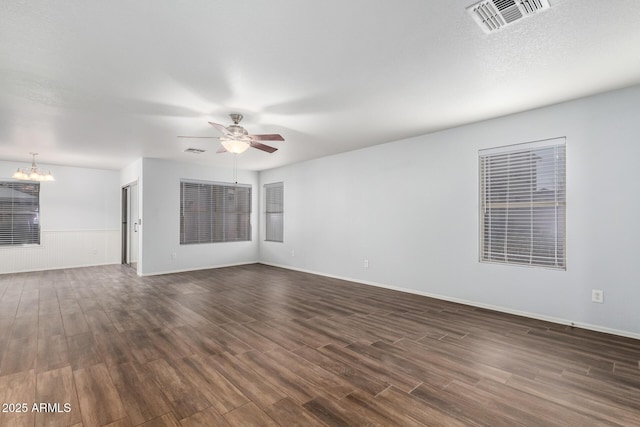 unfurnished room featuring dark wood-style floors, ceiling fan with notable chandelier, and visible vents