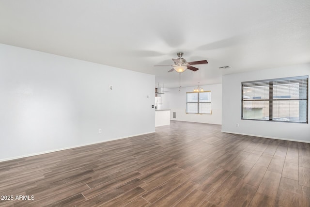 unfurnished living room with baseboards, visible vents, dark wood-style flooring, and ceiling fan with notable chandelier