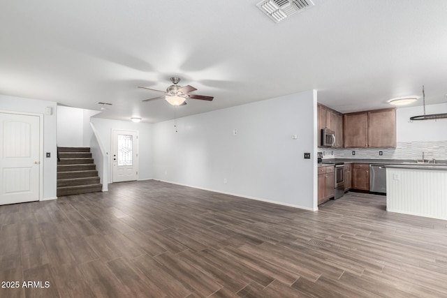 unfurnished living room with dark wood-style flooring, stairway, visible vents, and a ceiling fan